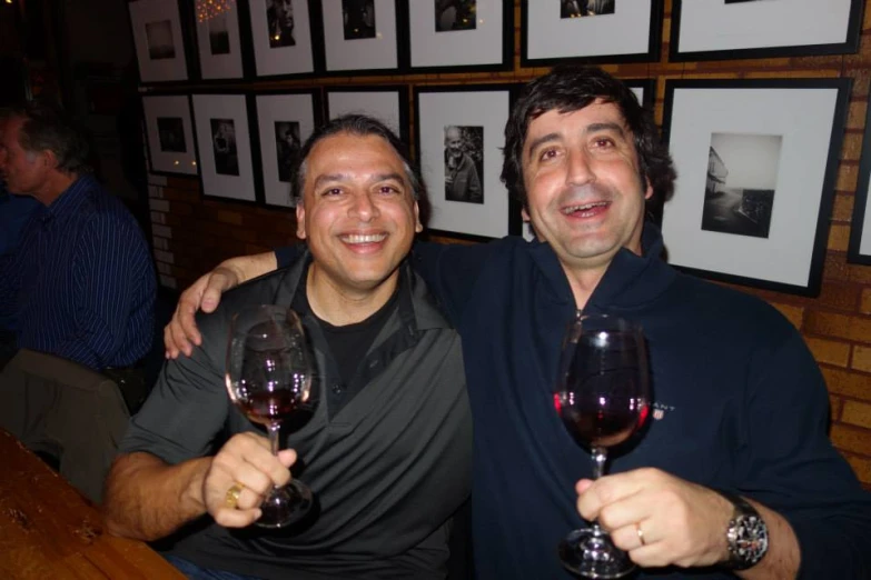 two men holding glasses of wine in their hands