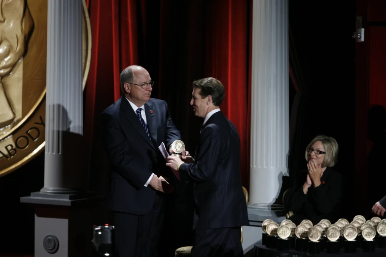 two men in suits shaking hands with people