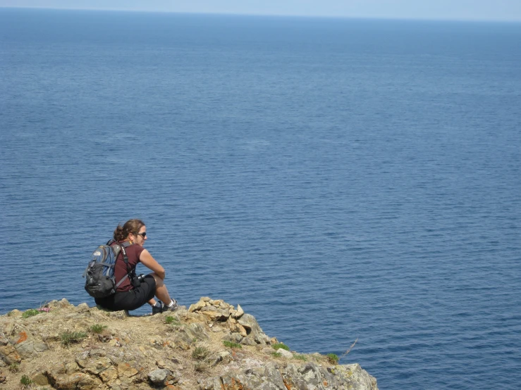 a person sitting on top of a mountain near the ocean