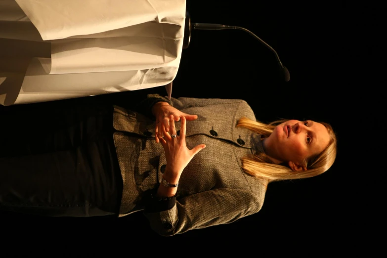 a woman talking at a podium with a table