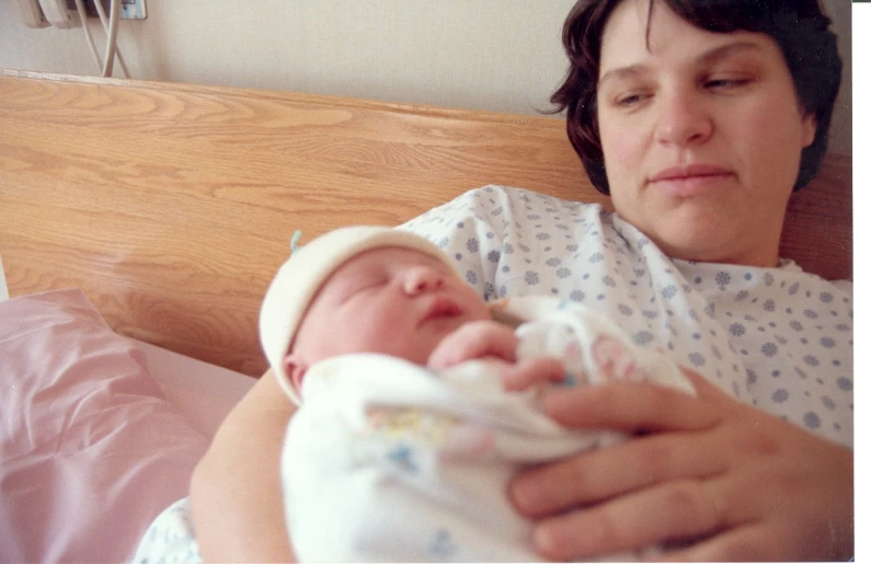 a woman is holding her baby in bed