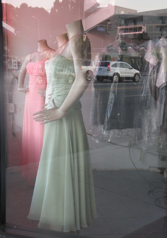 mannequins in dress and shoes on display behind glass