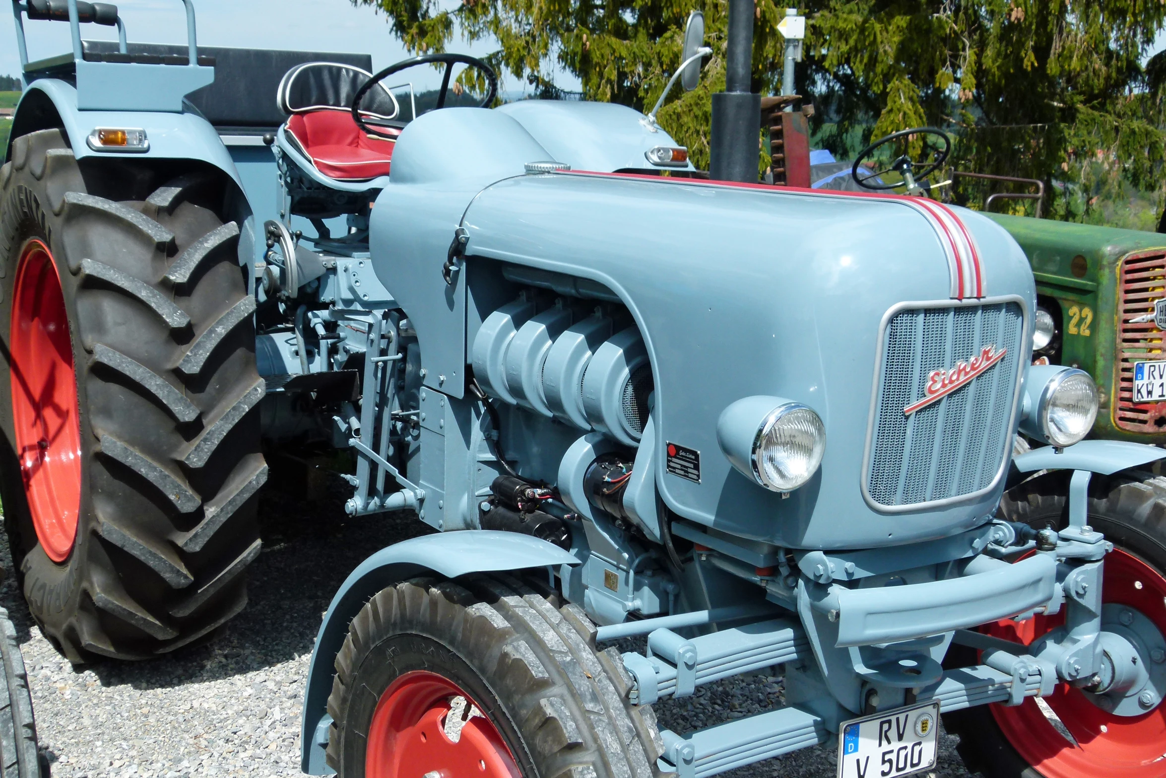 a blue and red farm tractor parked next to some other old tractors