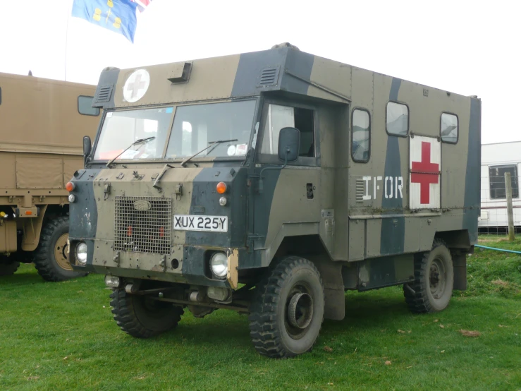 a military truck is parked on the grass near other vehicles