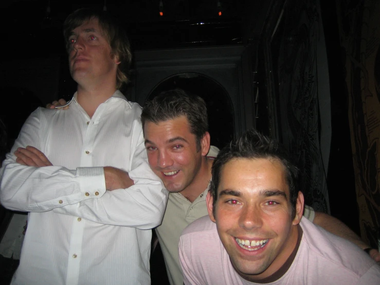 three smiling men are standing together in a restaurant