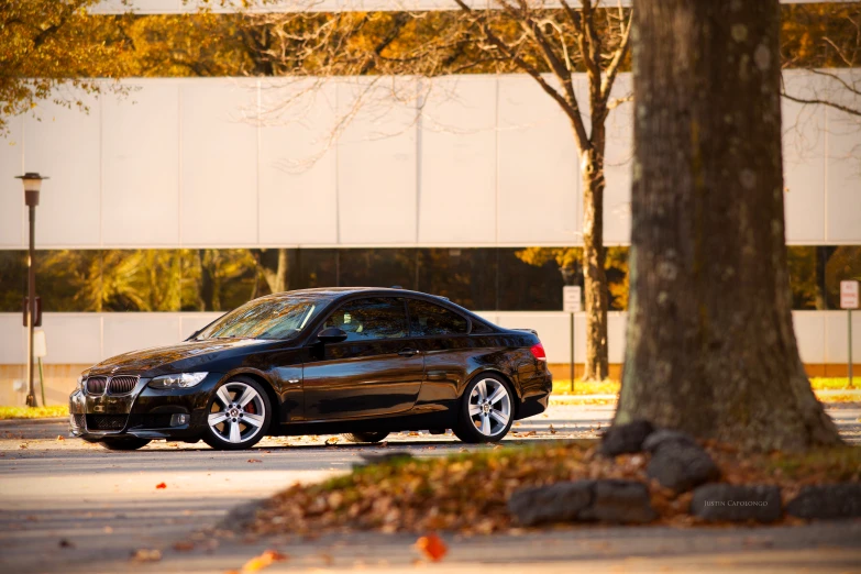 the black car is parked in front of trees