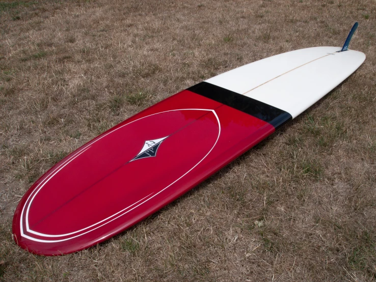 a red and white surfboard laying on the ground