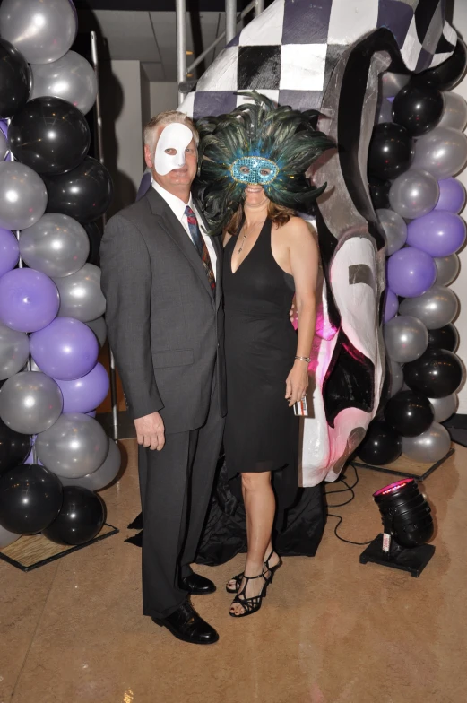 two people wearing masks standing in front of balloons