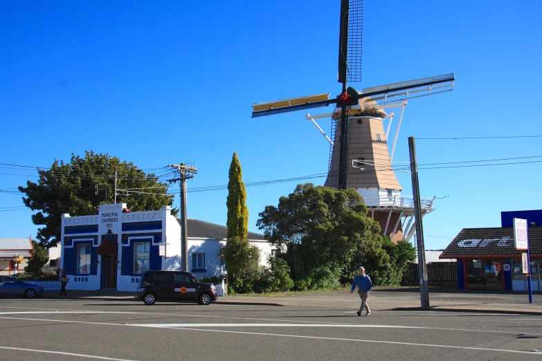 a windmill in the street with cars parked near it