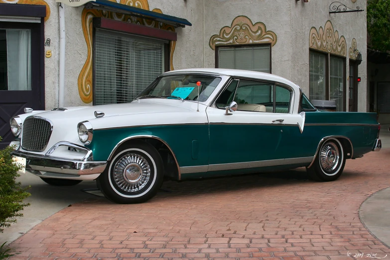 an old car is parked on the brick sidewalk