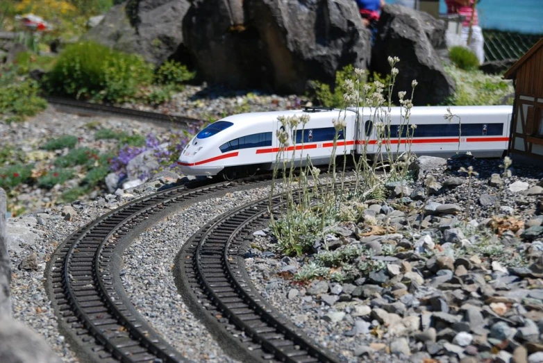 a small white and red train going along railroad tracks