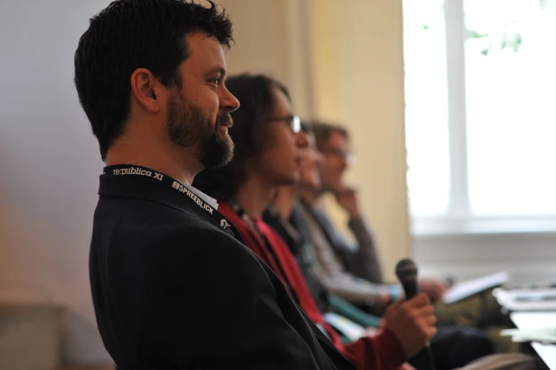 a group of people sitting in a row holding microphones