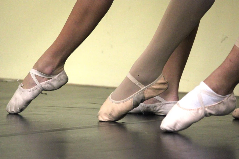 feet and ballet shoes in a line on the dance floor