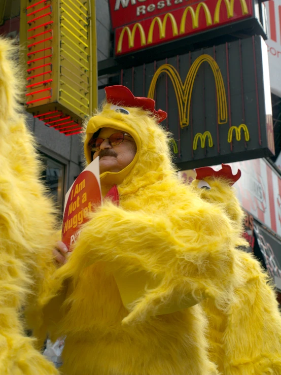 a large yellow chicken standing in front of mcdonald's