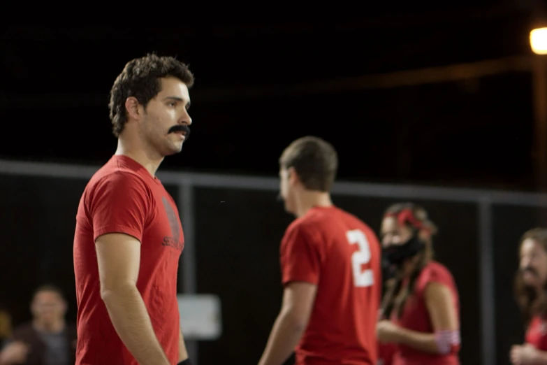 a couple of men wearing red shirts in front of people