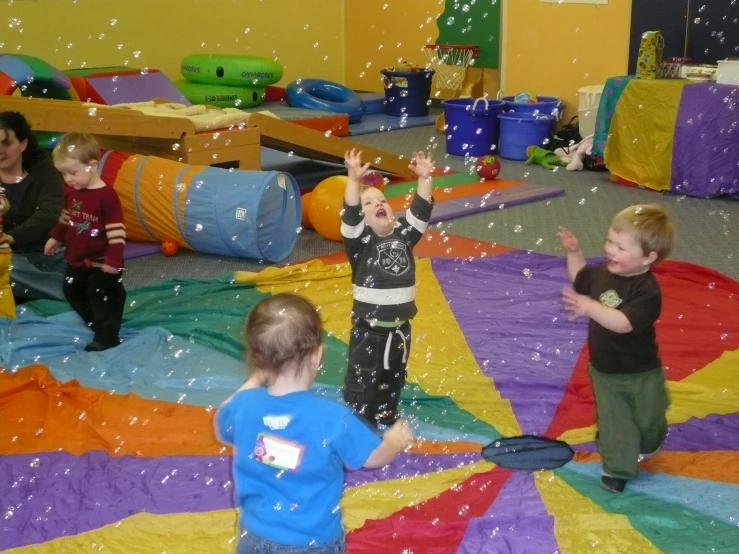 a couple of little boys standing next to each other on a blanket