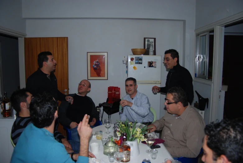 several people are around a table talking and drinking