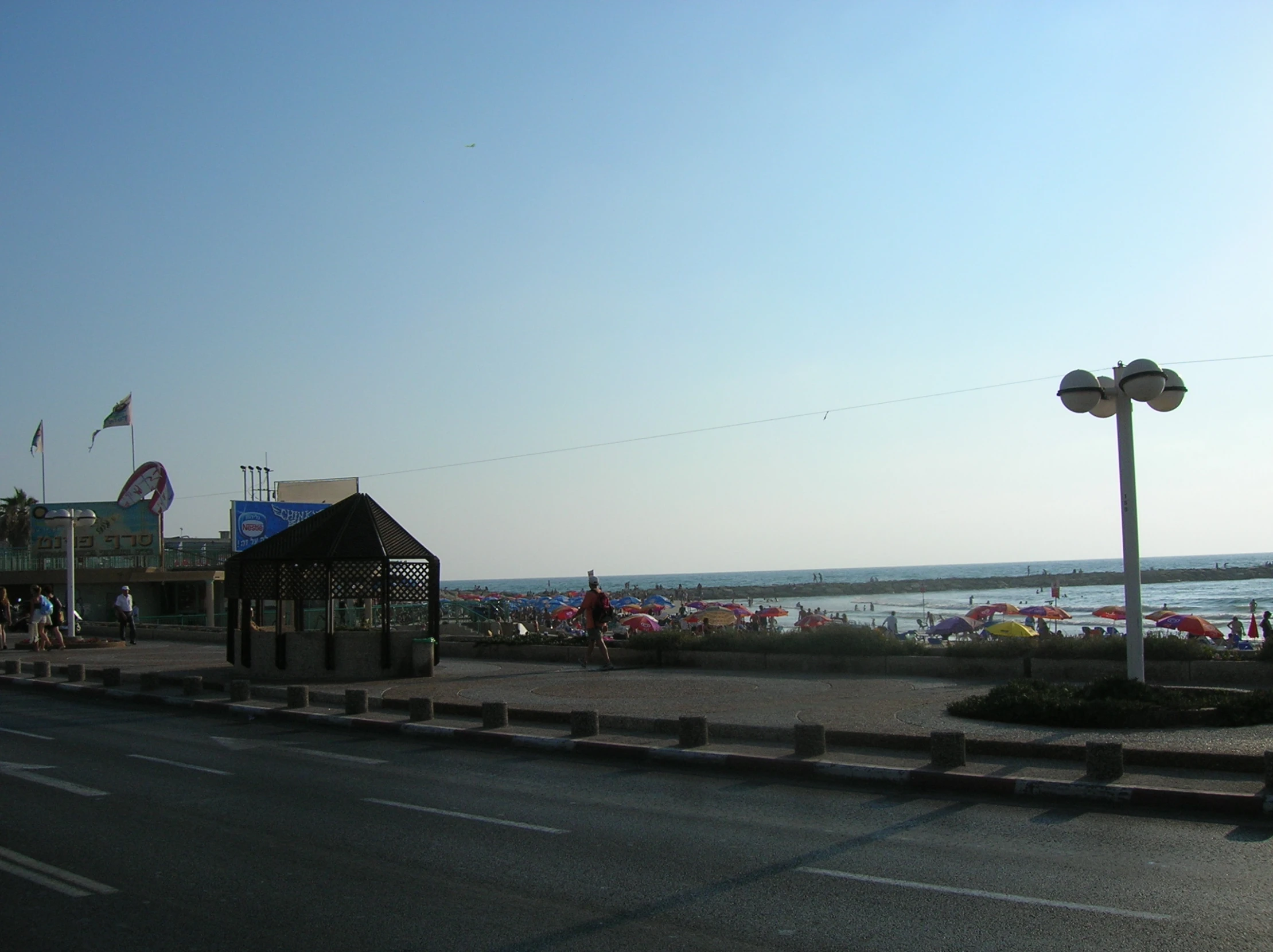 a road with people sitting on beach chairs under umbrellas