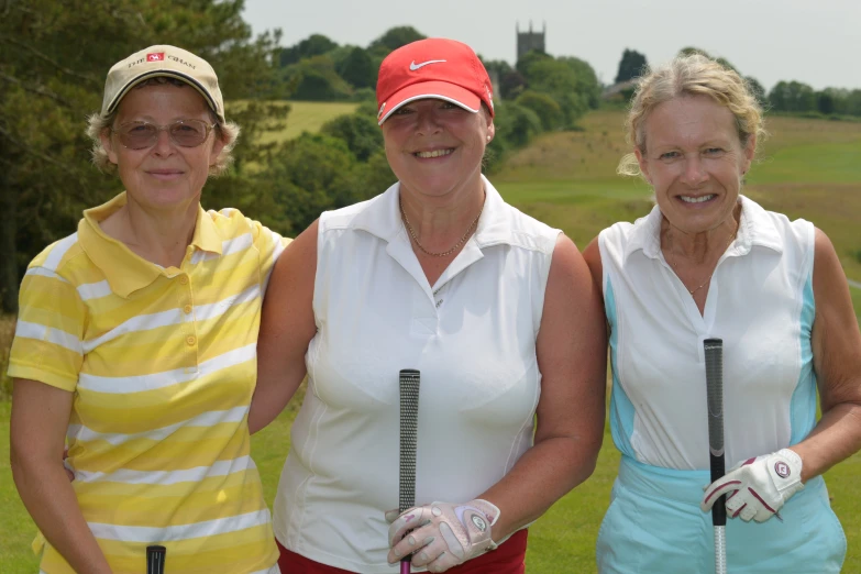 three women stand together in golf clothes