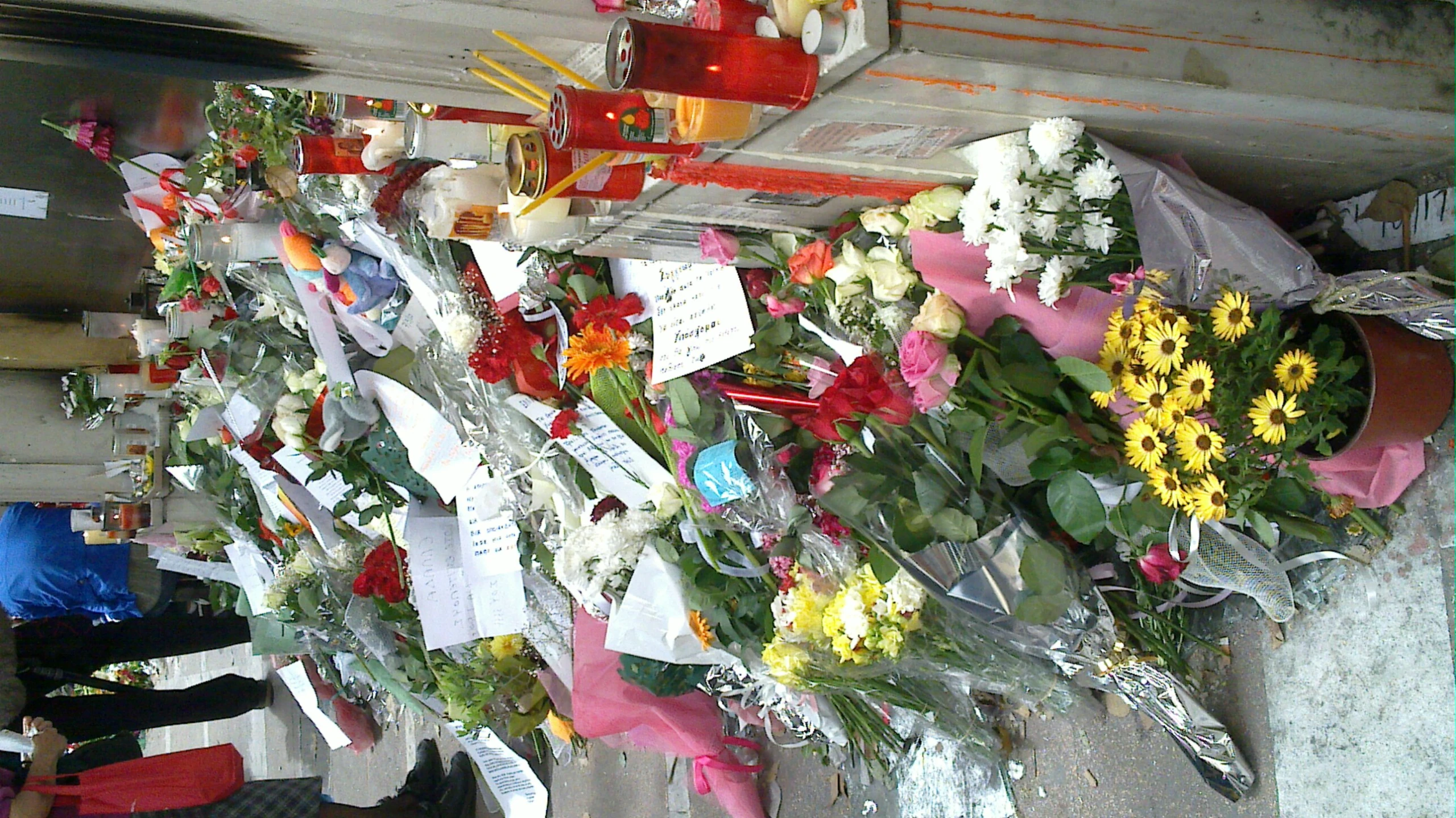 many flowers and candles line up in front of a building