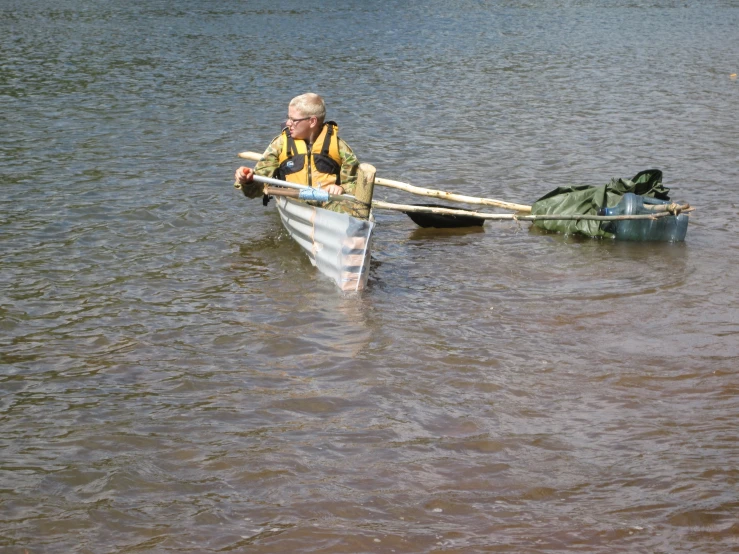 a man wearing a yellow vest is rowing a canoe