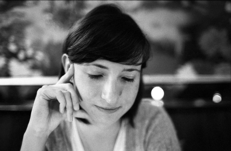 a woman looking at her cell phone sitting in front of a candle