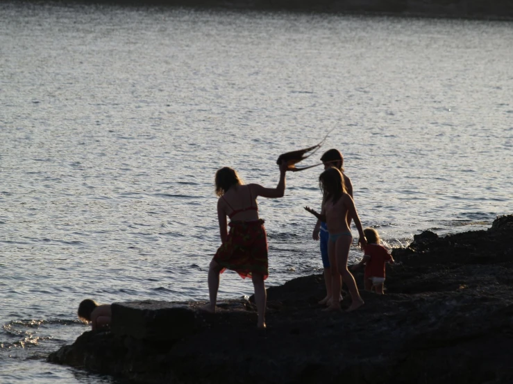 a family standing on a rock looking at the water