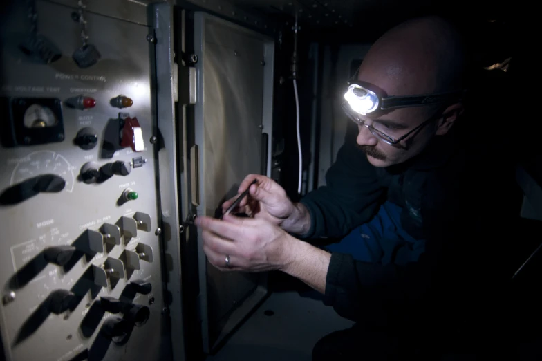 a man in glasses working on some electrical equipment