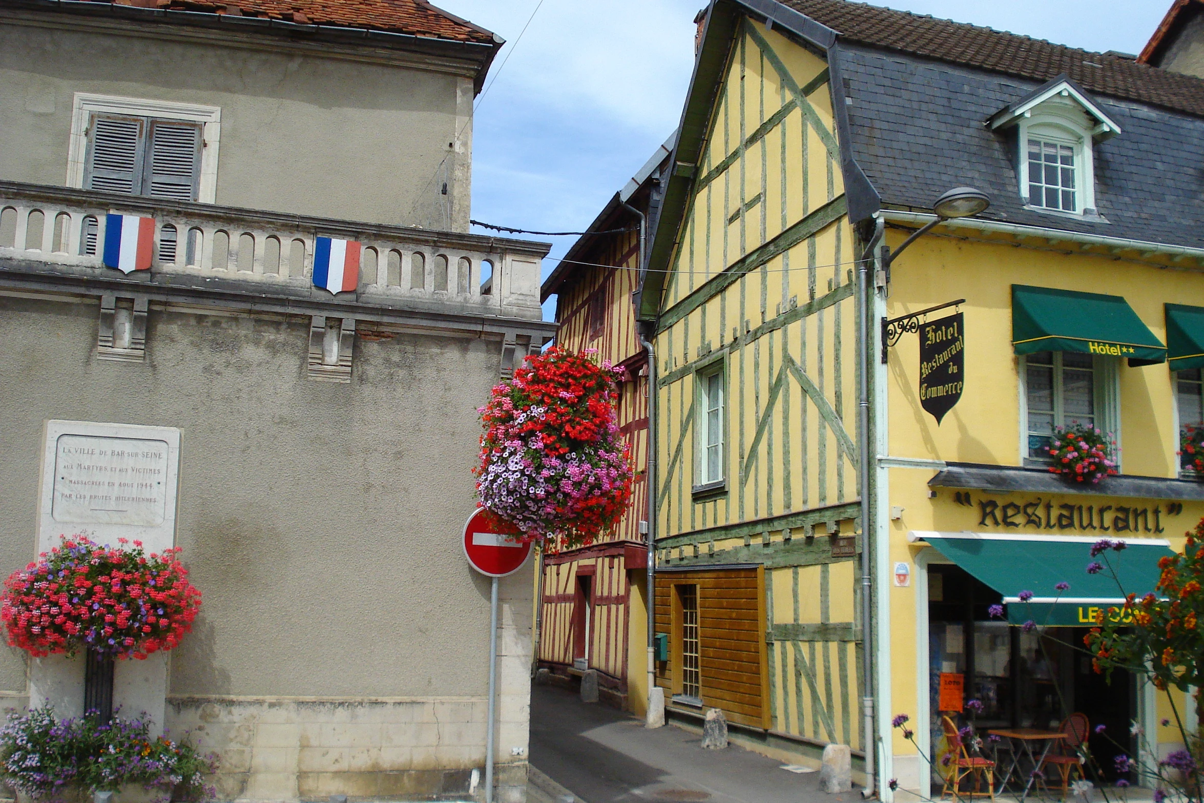 buildings lining a street with store fronts and hanging flower baskets