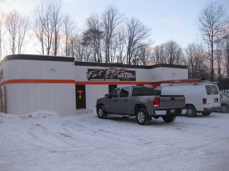 two trucks parked in front of a shop on a snowy day