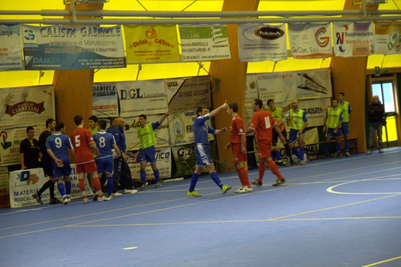 soccer players in red and blue jerseys playing on a blue court