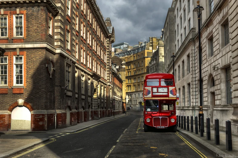 the red double decker bus is driving down the street