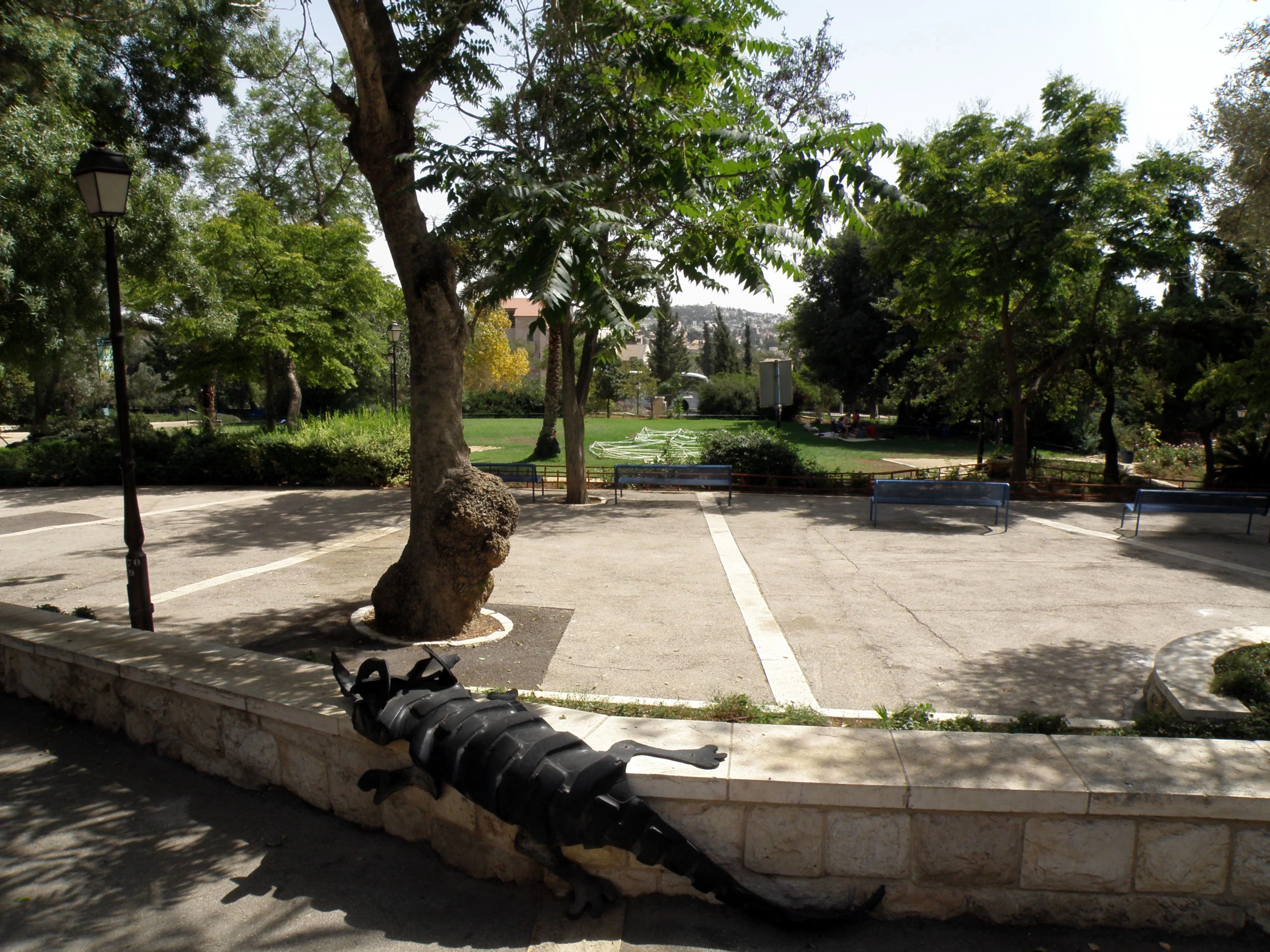 the statue of a giant dragon sits on the curb by a tree