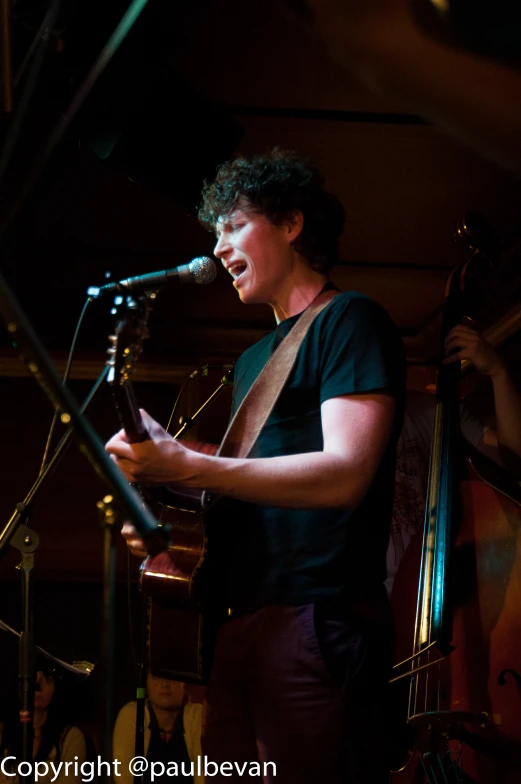 a man playing the guitar while singing into a microphone