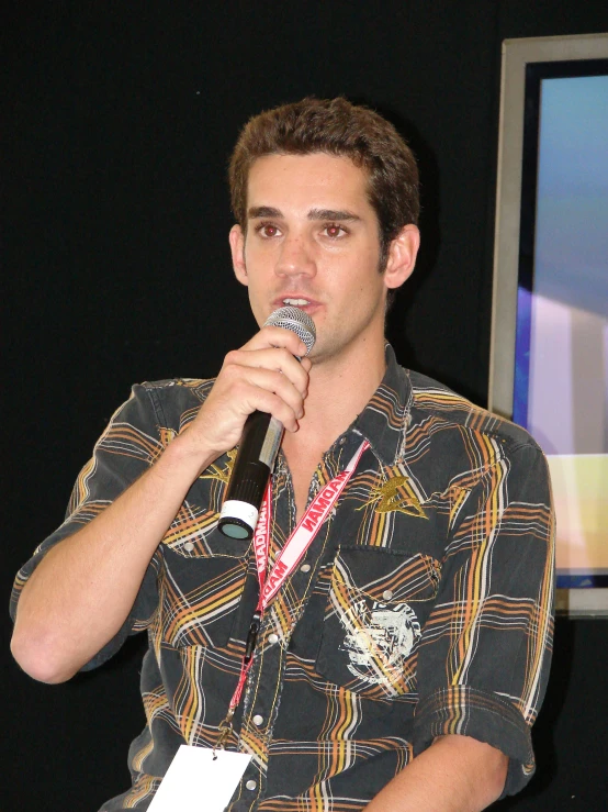 a man in plaid shirt holding a microphone