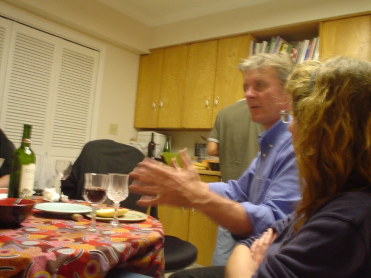 two people talking with other people at a dining room table