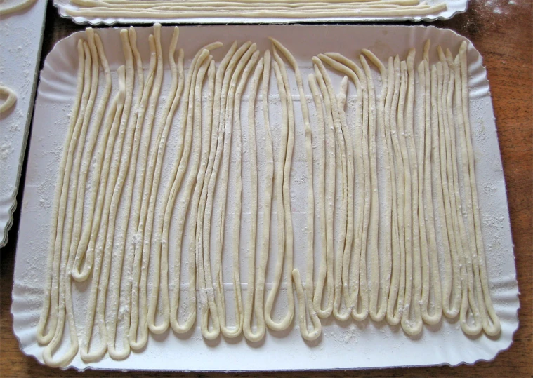pasta is prepared on a pan with wooden spoons