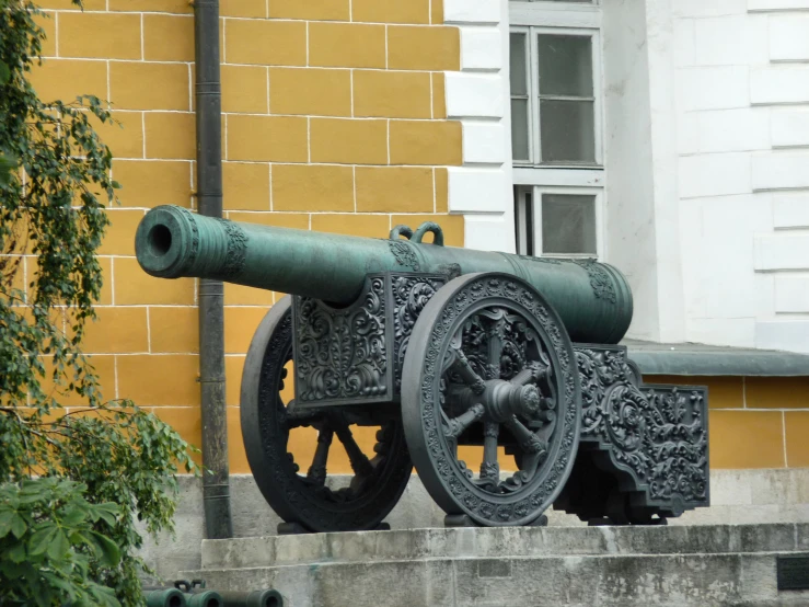 a cannon with a decorative body sits on a cement staircase