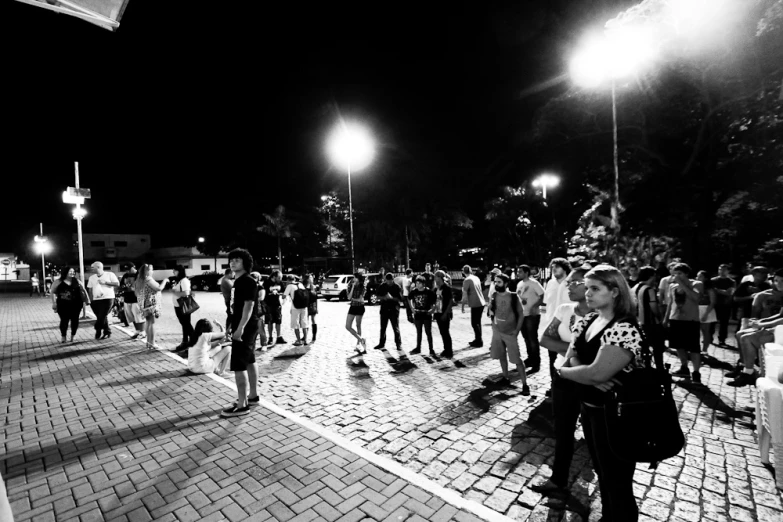 people standing in the street at night near street lamps