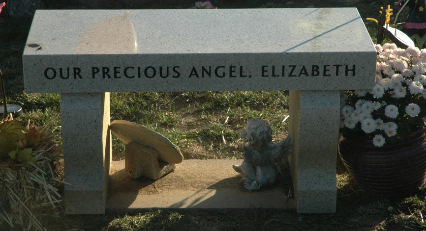 a monument surrounded by flowers near the path