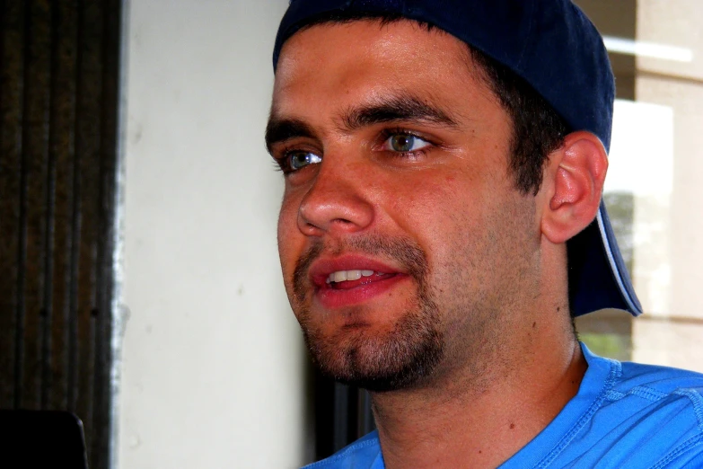 man with a blue hat standing by a building