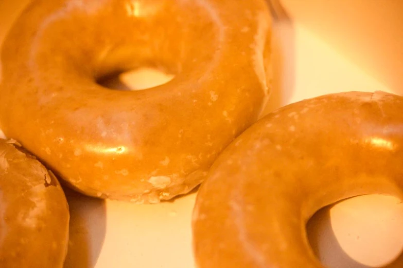 three donuts in a white paper box with orange wax