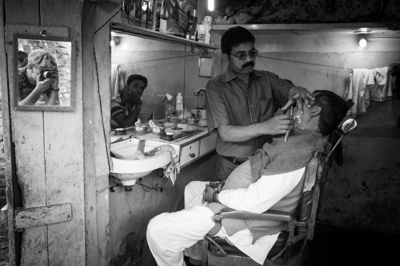 man getting hair cut with two men in a bathroom