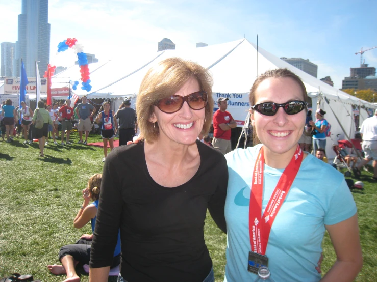 two woman are posing for a picture while other people stand in the background