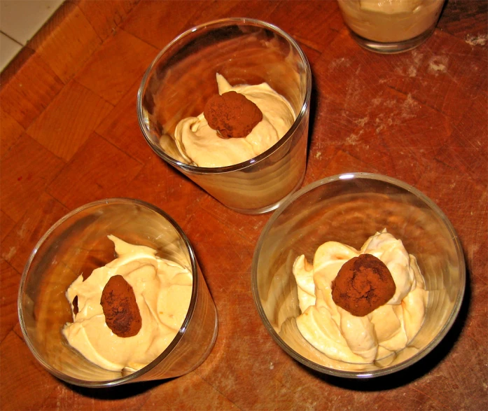four bowls filled with desert items on top of a wooden table