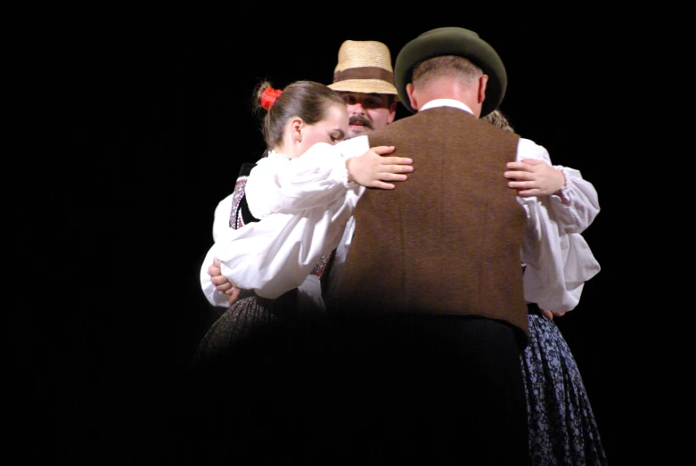 a man hugs another woman while she is hugged