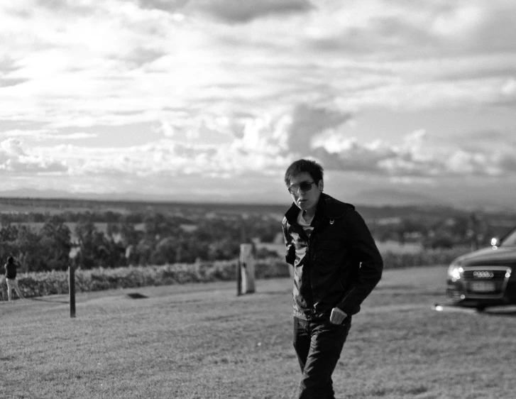 a man on his skateboard in the grass near some cars