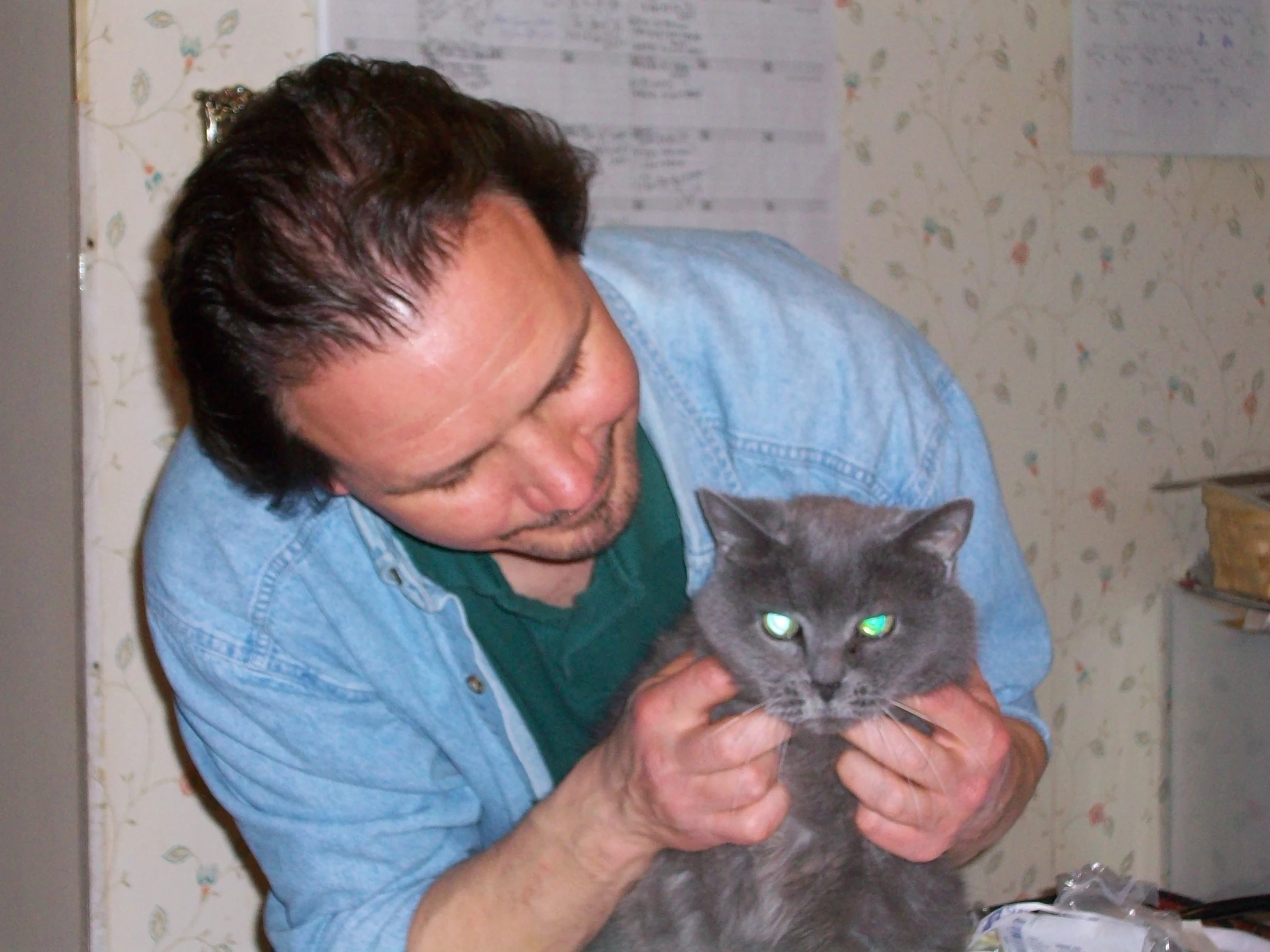 man holding a cat with one green eyes
