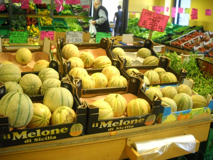 a fruit stand with melons, onions and squash
