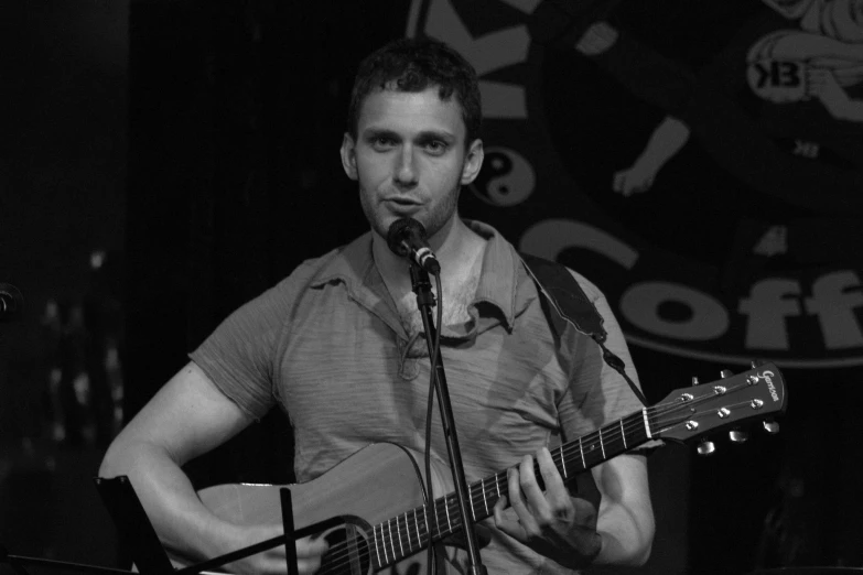 a man holding a guitar near a microphone